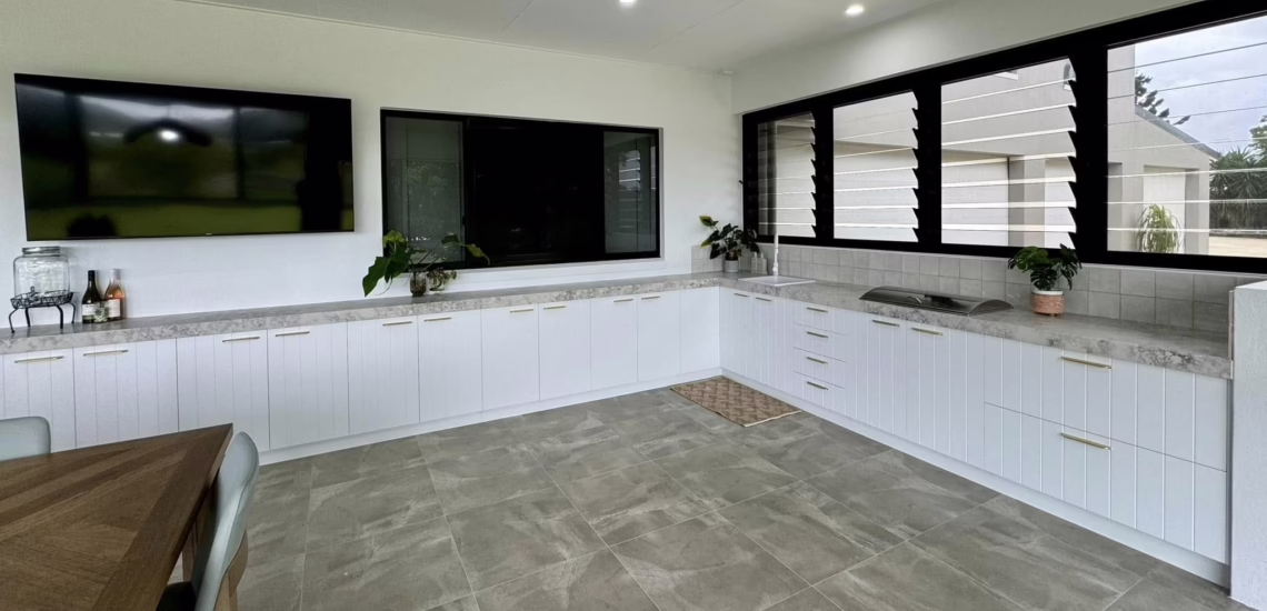  Spacious modern kitchen with white cabinets, large TV screen, and dining area.