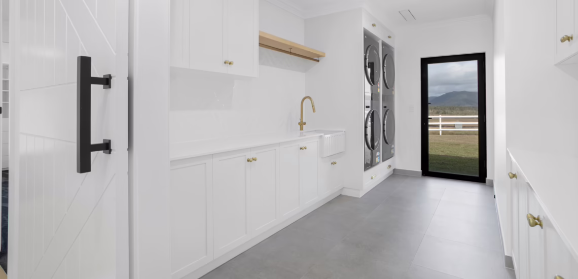 Modern white laundry with gold fittings and double stacked appliances built by NV Builders in Mackay
