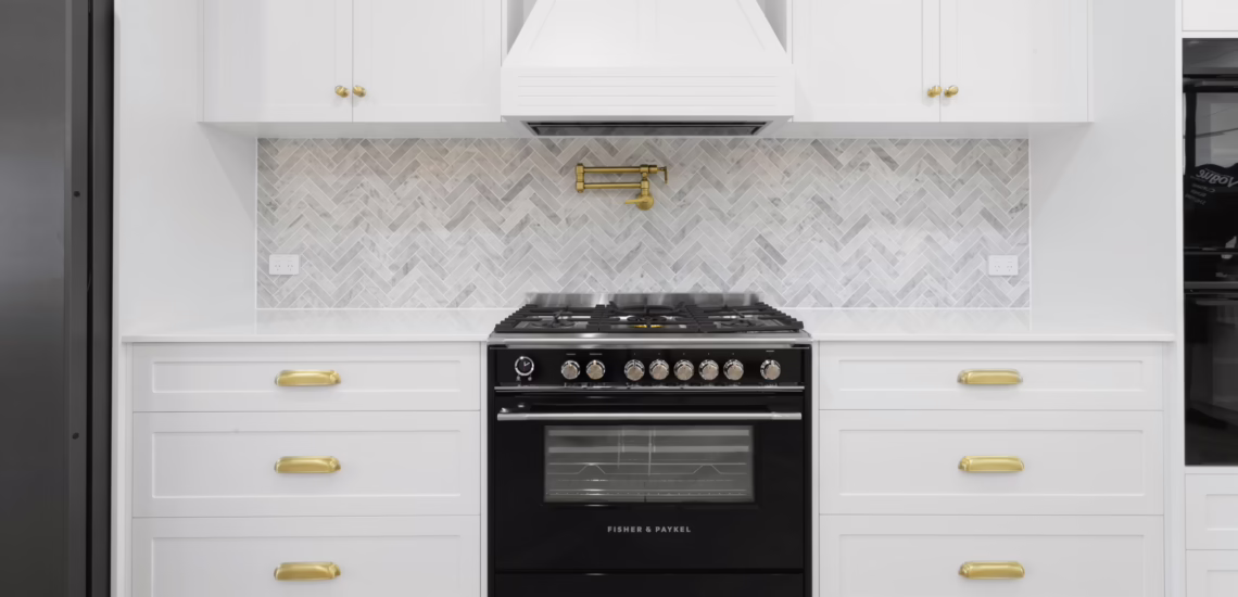 Black oven and marble herringbone splashback in white kitchen by NV Builders Mackay