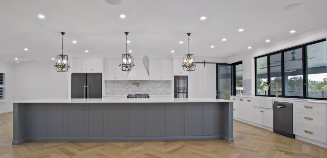 Large family kitchen with shaker cabinets and pendant lights by NV Builders Mackay