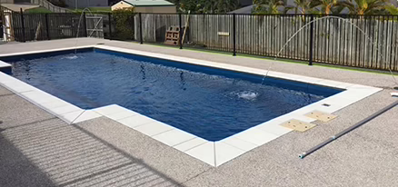 Modern backyard swimming pool with water features